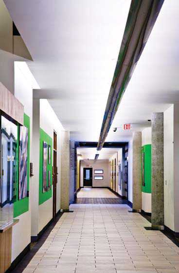 A photograph illustrating the use of linear overhead lighting along the centre of a hallway to assist with navigation. High colour contrast used at the edge of the floor and base of the walls distinguishes width and also aids with navigation.