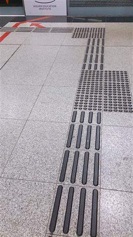 Indicateur tactile de guidage sur une surface de marche, constitué de barres allongées disposées selon un motif linéaire.
