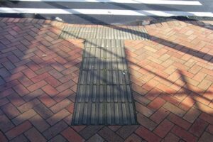 A good example of curb ramps at a mid-block crossing. Note that directional TWSIs are required to assist people impacted by blindness identify the presence of the curb ramp.