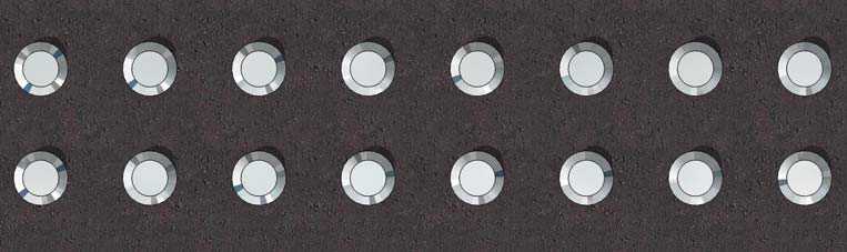 Indicateur tactile d’éveil de la vigilance sur une surface de marche, constitué de dômes tronqués en relief disposés selon un motif de grille.